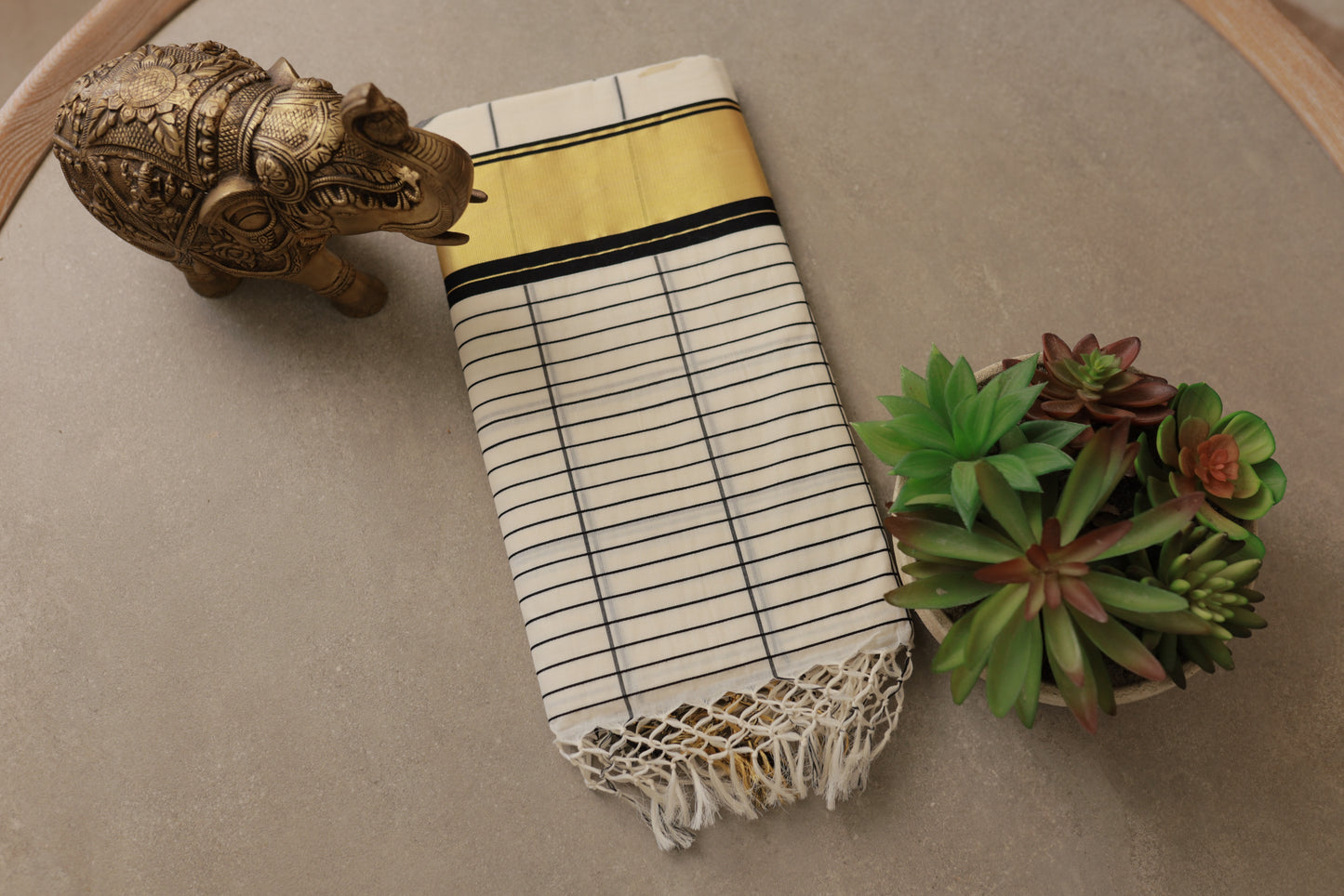 Pure Handloom Black Checks Kasavu Saree folded flat, showing the golden kasavu border and tassel fringe