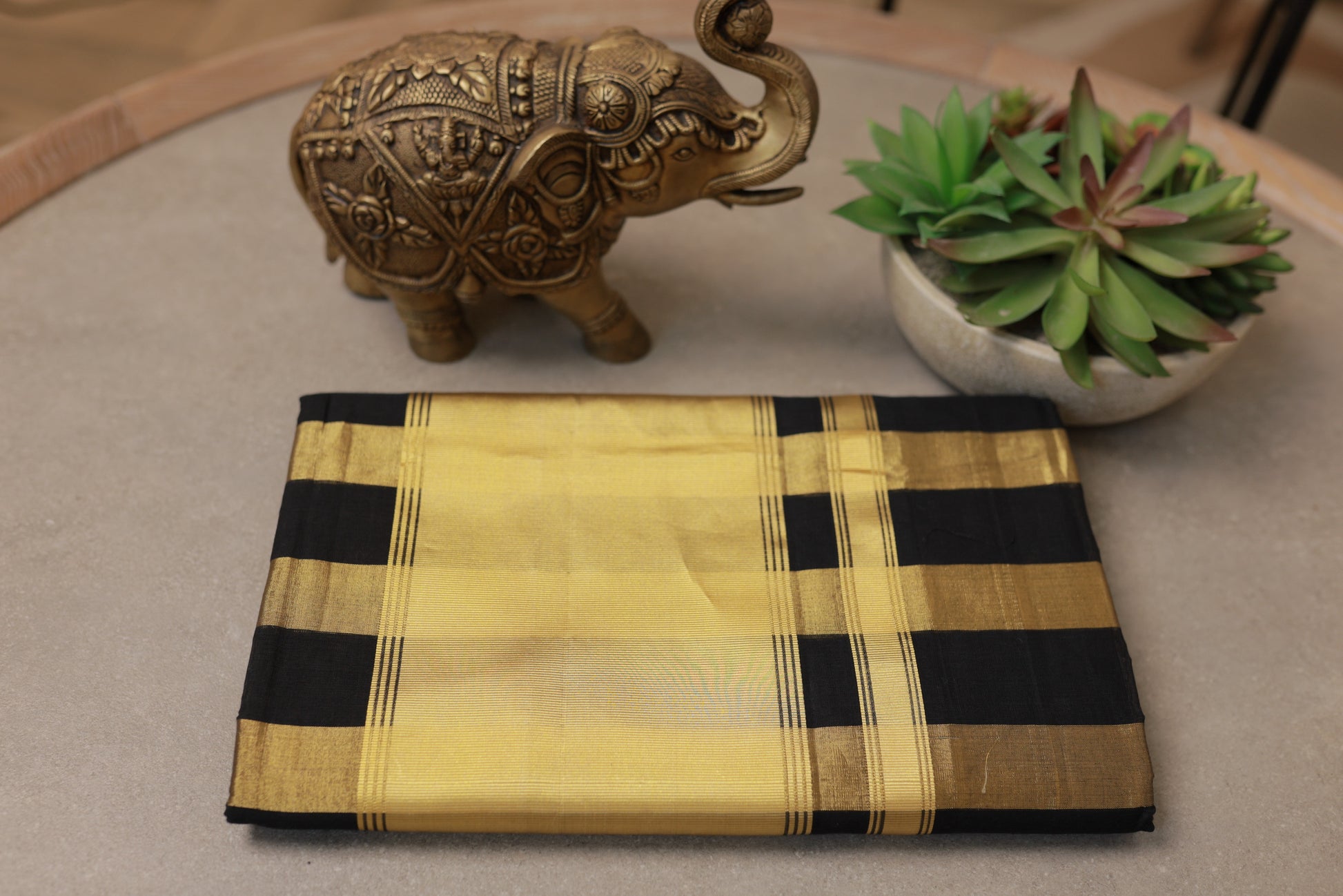 The Pure Handloom Black & Gold Striped Kerala Saree folded, showing the gold kasavu border and black checks