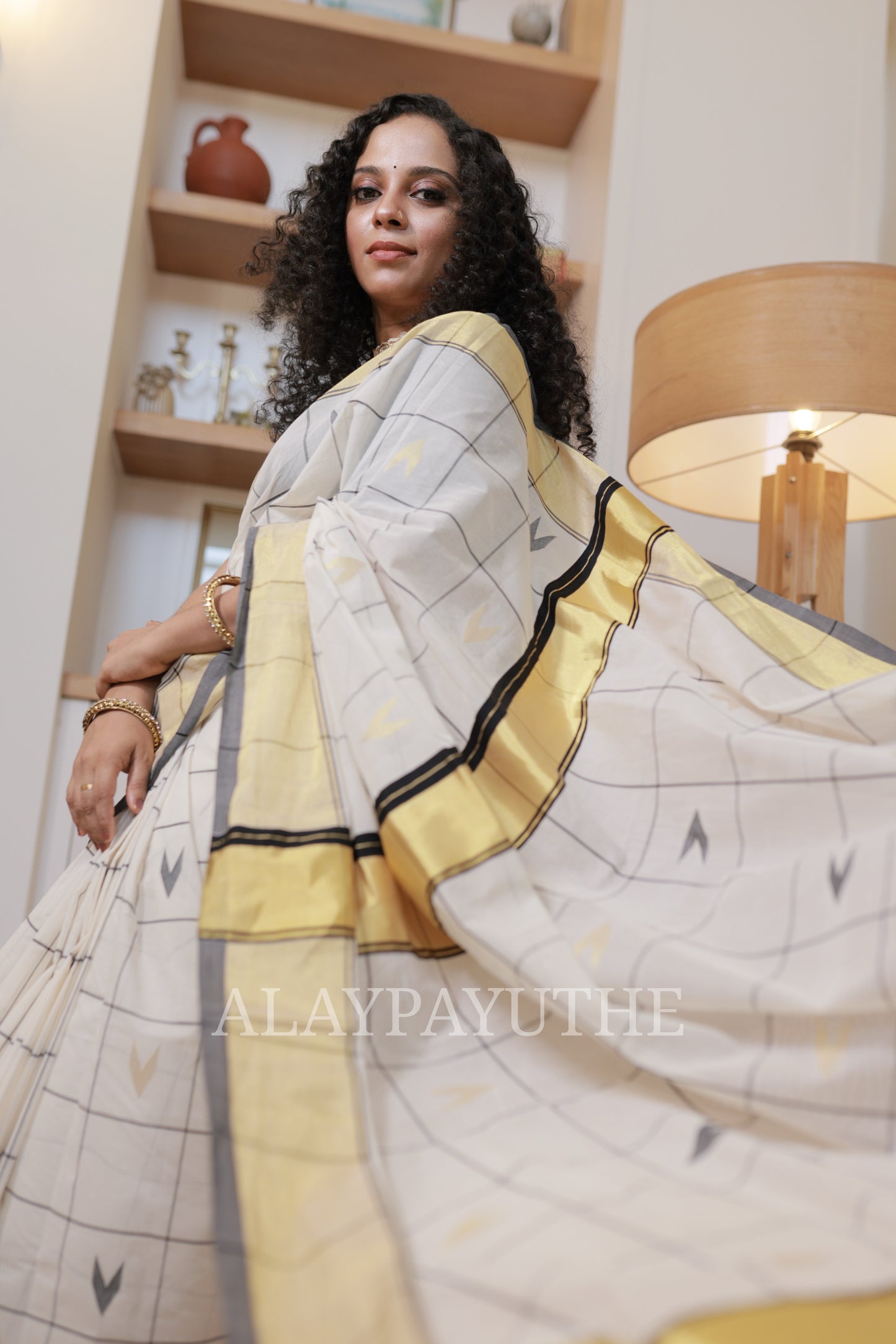 Pure Handloom Black Checks Kasavu Saree, model holding the pallu open to show the checked body and golden kasavu border