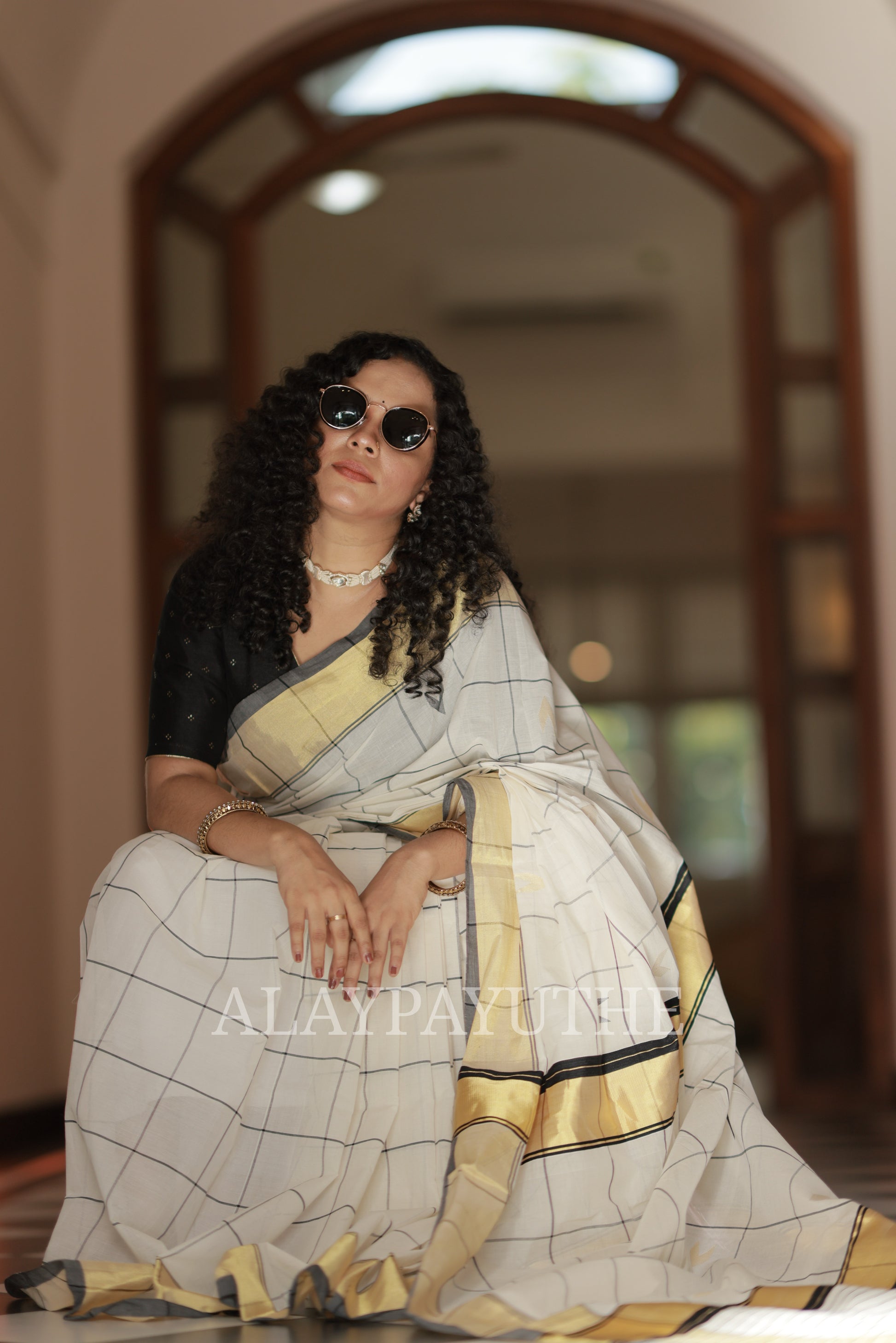 Pure Handloom Black Checks Kasavu Saree on seated model, front view showing the checked drape and golden kasavu border